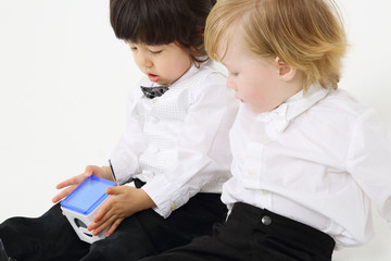 Two little cute boys play with wireless radio on white