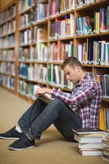 Serious student sitting on library floor reading