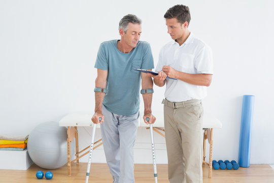 Therapist discussing reports with disabled patient in gym hospit