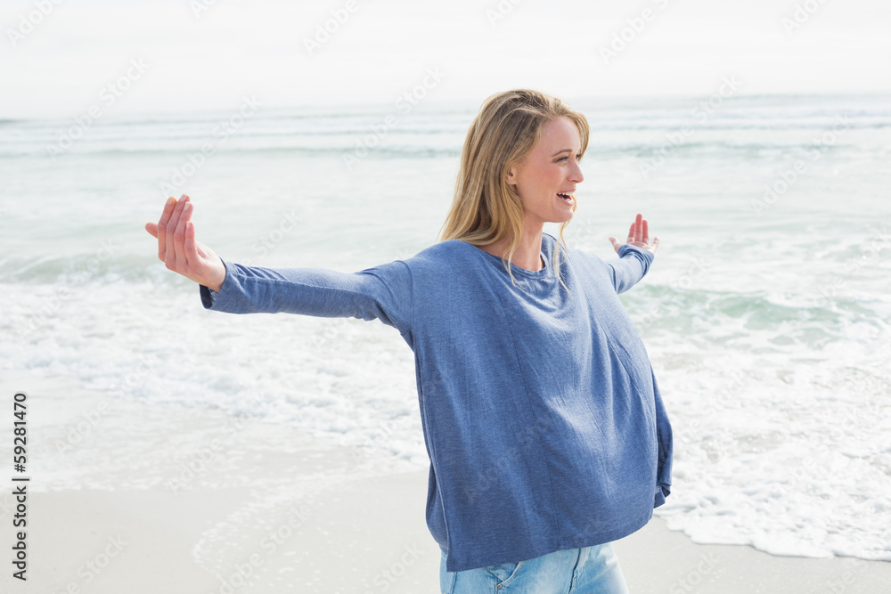 Wall mural woman standing with arms outstretched at beach