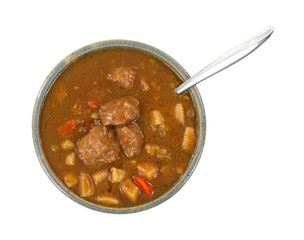A bowl of meatball stew with a spoon