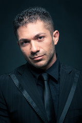 Obraz premium Young man close up portrait against dark background.