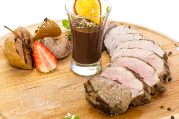 meat roasted on a grill with vegetables on a wooden plate