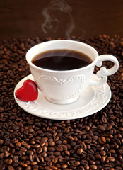 White cup of coffee with red heart on coffee beans