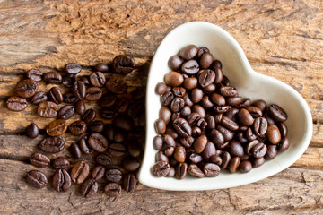 Coffee beans in a cup heart on wooden background