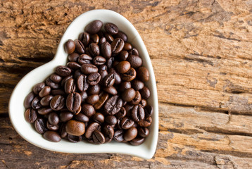 Coffee beans in a cup heart on wooden background