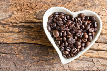 Coffee beans in a cup heart on wooden background