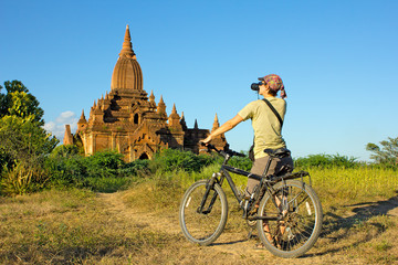 girl photographer on a bicycle takes a picture of the temple in Bagan, Myanmar(Burma)
