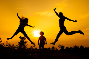 Fototapeta na wymiar Happy family jumping on the road in the sunset time.
