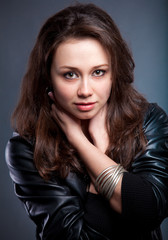 Naklejka premium portrait of sexy brunette in leather coat holding hands on neck