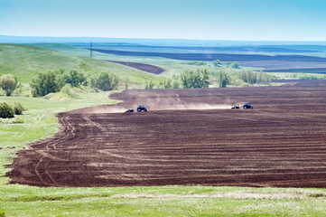Два трактора с сеялками работают в