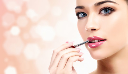 woman applying lips makeup with cosmetic brush