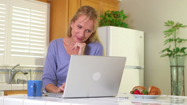 Adult woman drinking morning coffee while using computer