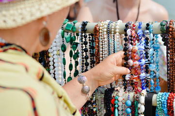 Woman choosing jewelry in row of necklaces and bracelets