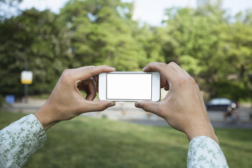 Person holding Smartphone to take a picture in park