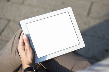 Businessman in a park holding a touch screen device.