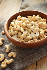 Raw cashew nuts in wooden bowl on rustic table