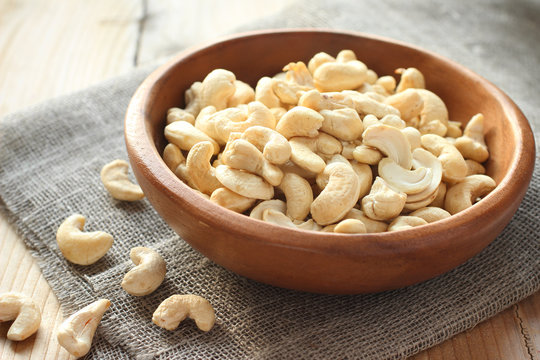 Raw cashews in wooden bowl on sackcloth