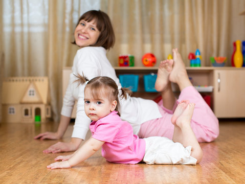 Mother and kid doing exercises laying on the floor in home inter