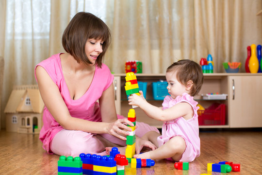 Happy mother and kid play with toys at home interior