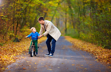 Obraz premium father teaches son to ride the bicycle