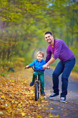 Fototapeta na wymiar father teaches son to ride the bicycle
