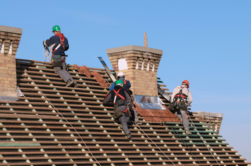 Man working on the new roof - obrazy, fototapety, plakaty