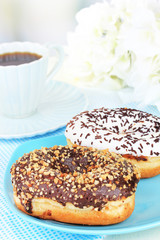 Sweet donuts with cup of tea on table on light background