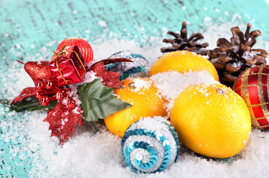 Christmas tangerines and Christmas toys on wooden table on snow