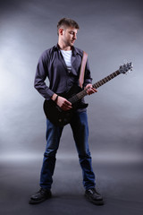 Young musician playing  guitar on gray background