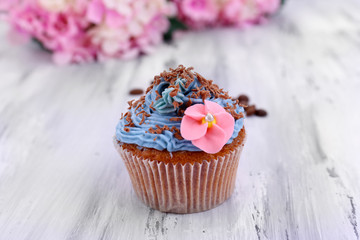 Tasty cupcake with butter cream, on color wooden background