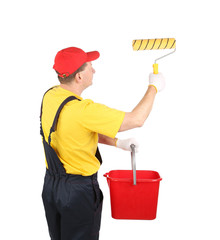 Worker in hardhat paints with bucket.