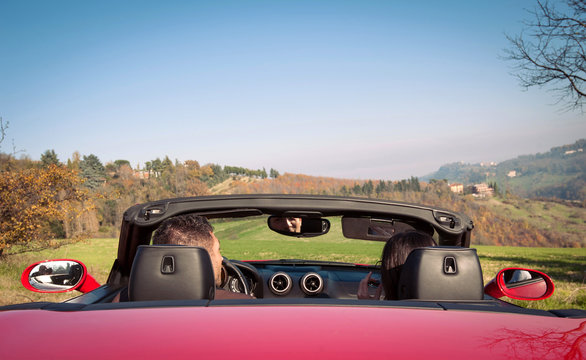 Young couple inside cabriolet car with view of countryside.