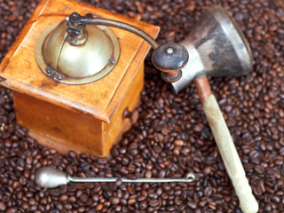 coffee grinder and copper pot on roasted beans