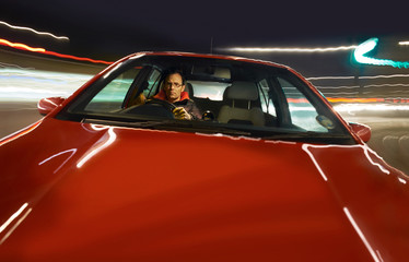 A man driving a red sports car at night.