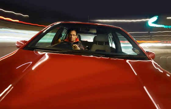 A Man Driving A Red Sports Car At Night.