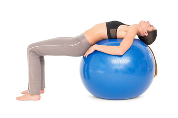Side view of a fit woman stretching on fitness ball