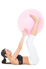Fototapeta na wymiar Side view of a fit woman exercising with fitness ball