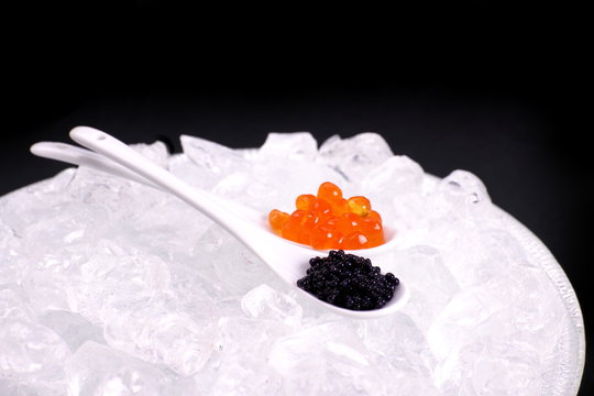 Porcelain spoon full of red and sturgeon black caviar