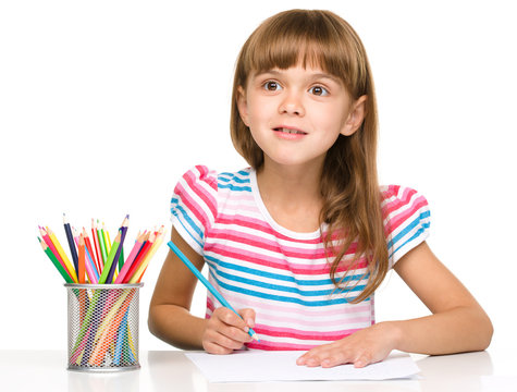 Little girl is drawing using pencils