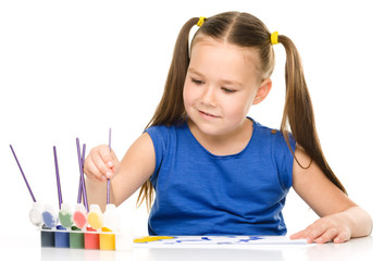 Little girl is painting with gouache