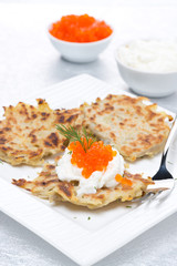 potato pancakes with red caviar and sour cream, vertical