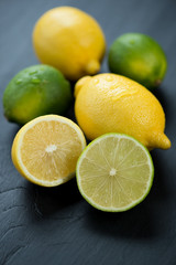 Fototapeta na wymiar Ripe lemons and limes over black wooden background