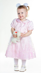 Little girl standing in full growth with toy and smiling
