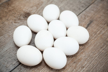 Ten chicken white eggs laying on wooden floor