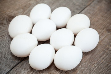 Ten chicken white raw eggs laying on wooden board