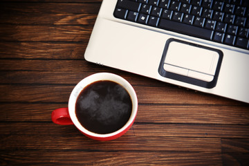 Laptop and coffee cup on wood table. View from above