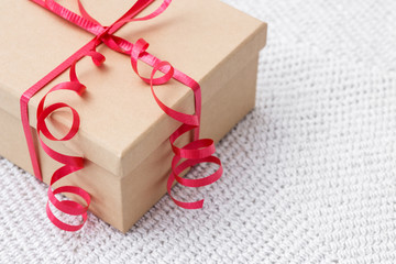 Gift with red ribbon on a knitted background