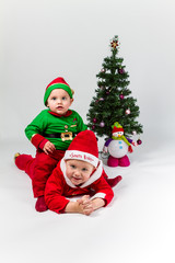 Two baby boys dressed as Santa Claus and Santa's Helper lying ne