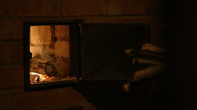 Putting firewood into the stove.